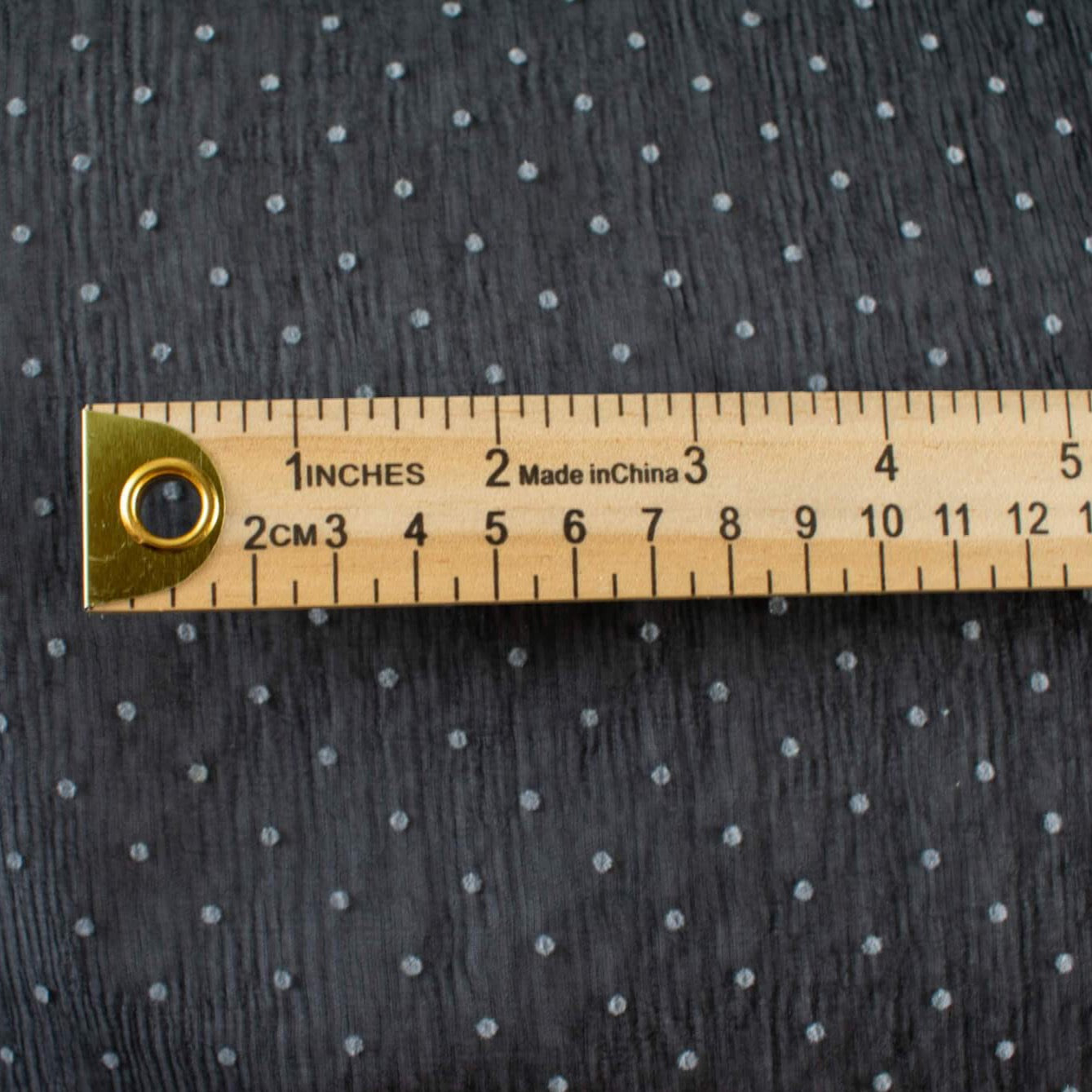 Classic black and off white polka dot is always elegant! Chiffon is sheer, has a beautiful drape and is popular in blouses, gowns, lingerie, flowy overlays, scarves, even trim. Perhaps you have seen it used as trim in those fabulous French Jackets! Photo of fabric with ruler demonstrating design scale.