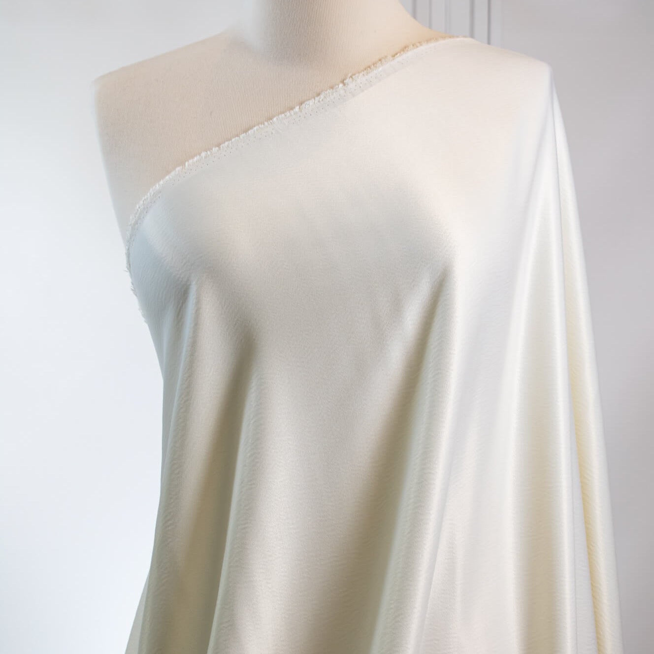 Steal the show in this NYC Designer pebble satin. A gorgeous light to medium weight off-white rayon satin that shimmers. Create a portrait worthy slip dress, bias skirt, or top! Close up fabric draped on dressform.