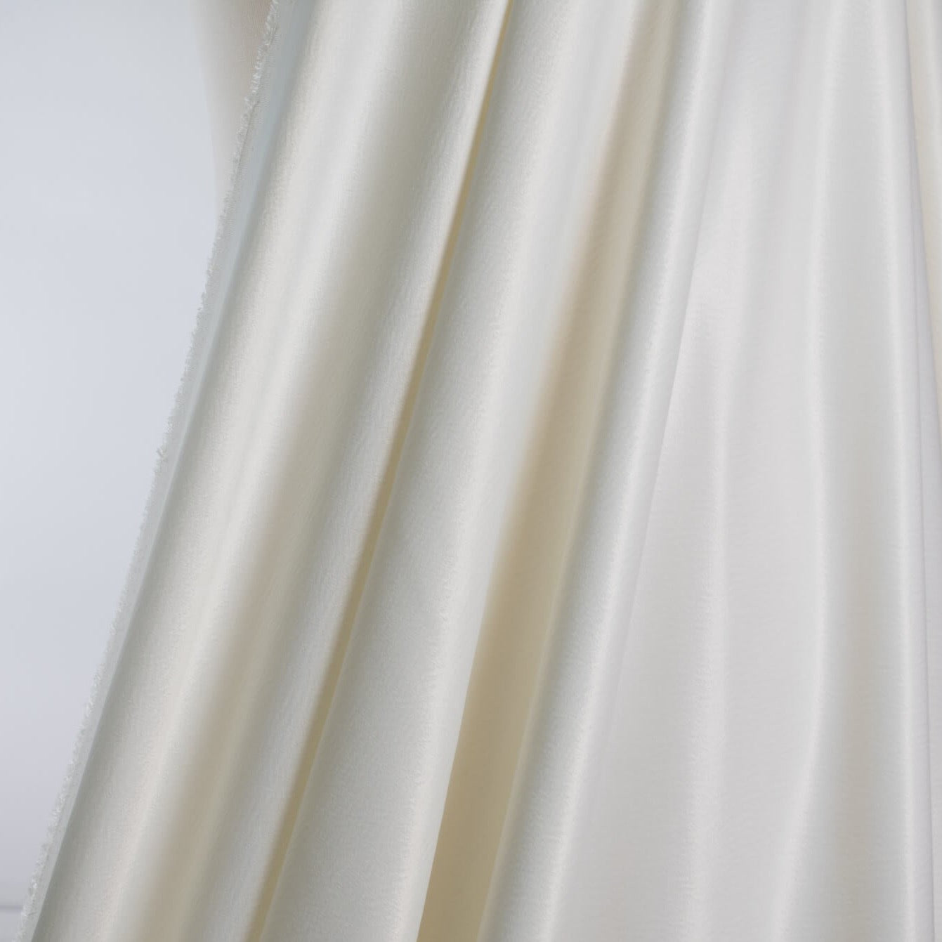 Steal the show in this NYC Designer pebble satin. A gorgeous light to medium weight off-white rayon satin that shimmers. Create a portrait worthy slip dress, bias skirt, or top! Image of fabric drape.