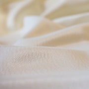Steal the show in this NYC Designer pebble satin. A gorgeous light to medium weight off-white rayon satin that shimmers. Create a portrait worthy slip dress, bias skirt, or top! Close up image.
