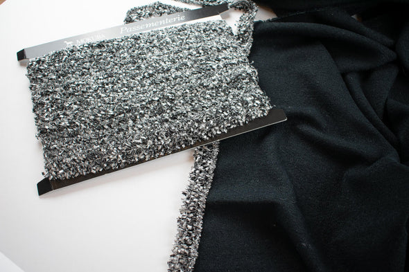 Mokuba Silver and Black passementerie pictured with black boucle fabric.
