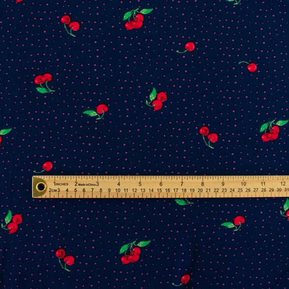 Have some fun with our navy and pink polka dot designer deadstock fabric by the yard adorned with vibrant red cherries. Made from high-quality polyester crepe, this fabric has a textured hand, lovely drape, and a vintage vibe. Image of pattern scale with ruler.