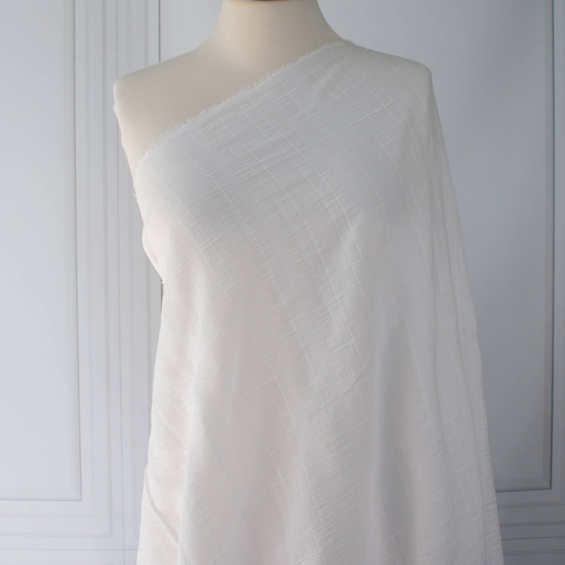 Close-up of white dimity designer fabric draped on dressform