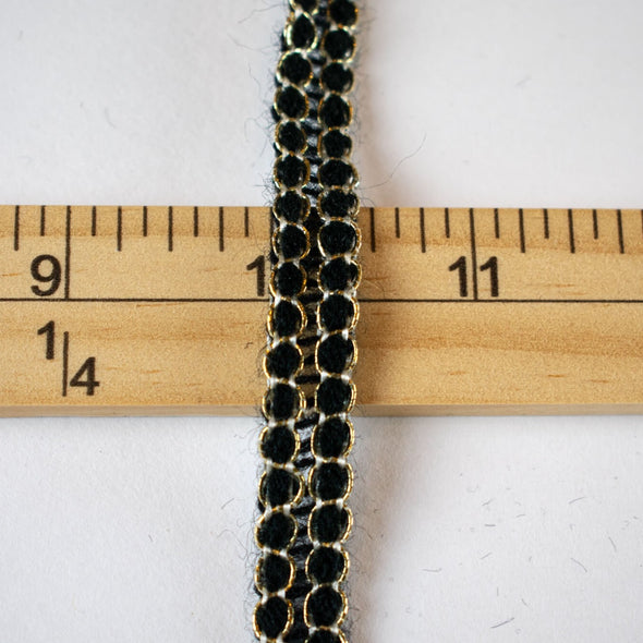 Create a luxurious touch of couture with our vintage trim as it’s metallic gold threading elegantly encircles soft black ribbons. It is sure to make any fabric you are working with sophisticated and glamourous. Photo of trim against ruler.