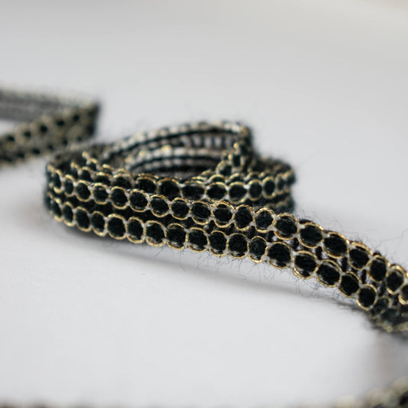 Create a luxurious touch of couture with our vintage trim as it’s metallic gold threading elegantly encircles soft black ribbons. It is sure to make any fabric you are working with sophisticated and glamourous. Close up of trim in a swirl.