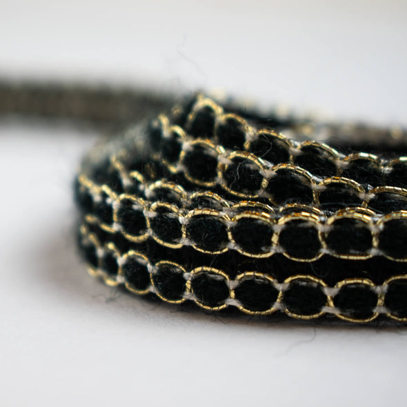 Create a luxurious touch of couture with our vintage trim as it’s metallic gold threading elegantly encircles soft black ribbons. It is sure to make any fabric you are working with sophisticated and glamourous. Close up.