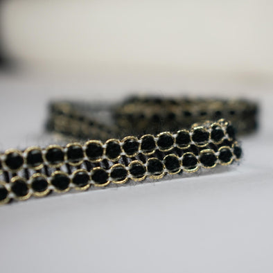 Create a luxurious touch of couture with our vintage trim as its metallic gold threading elegantly encircles soft black ribbons. It is sure to make any fabric you are working with sophisticated and glamourous. Close up photo.