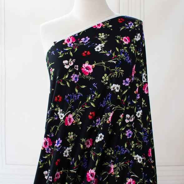 Create a look you’ll love in our timeless black DTY knit fabric with a floral print of pink, white, and purple flowers and soft green leaves. A gorgeous knit with a soft hand and fluid drape, perfect for making a garment that flatters!  Image of fabric on dressform.