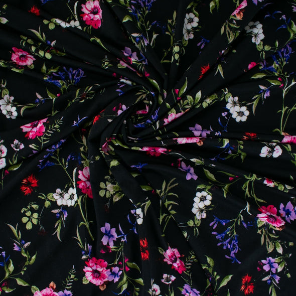 Create a look you’ll love in our timeless black DTY knit fabric with a floral print of pink, white, and purple flowers and soft green leaves. A gorgeous knit with a soft hand and fluid drape, perfect for making a garment that flatters!  Image of fabric swirled to show body.