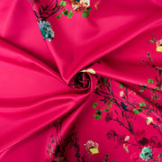 Couture dark pink duchesse satin fabric by the yard is perfect for standing out at weddings or any fancy event. With a gorgeous trailing floral vine, this dead stock fabric captures pure elegance. Originating from the Italian mills, and sourced from a designer who has dressed celebrities on the red carpet this densely woven matte satin has a smooth hand and fuller body, with a sponginess that would create a lovely column gown, corset top, or full skirt. Image of fabric fullness.