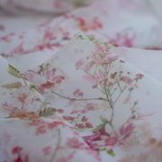 Close up image of Floral Couture designer soft white silk chiffon fabric with pink flowers and green leaves 