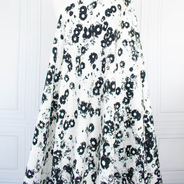 Image of couture black and white floral designer deadstock fabric by the yard! A modern floral design in black set against a creamy white is elevated by the soft "blistered" texture of this stunning jacquard. Perfect for wedding season. Fabric is draped on dressform.