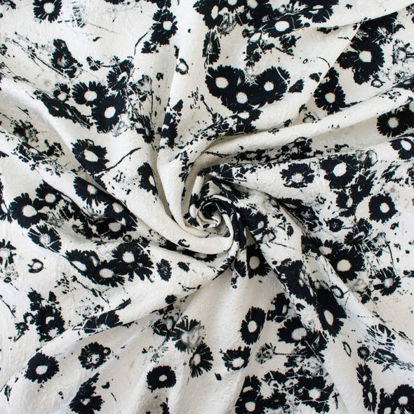 Image of couture black and white floral designer deadstock fabric by the yard! A modern floral design in black set against a creamy white is elevated by the soft "blistered" texture of this stunning jacquard. Perfect for wedding season.