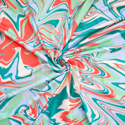 NYC Designer Abstract Jesery Knit designer deadstock fabric by the yard. A mid-weight opaque jersey knit with a soft, smooth hand and slight sheen. Shades of light blue, sea glass green, turquoise green, and coral evoke a playful and fun mood with colors hinting at 'Miami Vibes'. Image of fabric fullness.