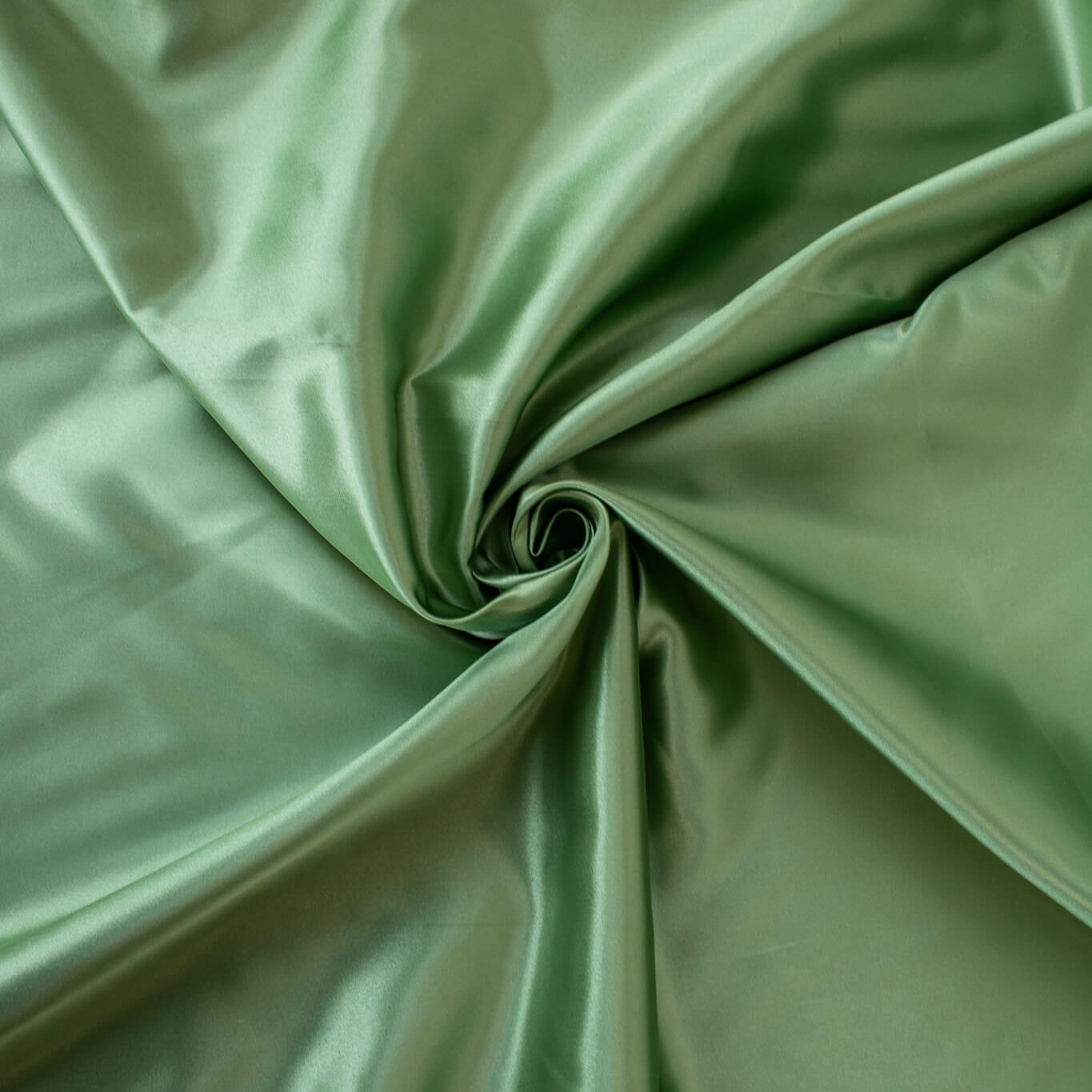 NYC Designer Polyester Satin designer deadstock fabric by the yard. Shimmery satin in a serene spring green is sophisticated and eye catching! &nbsp;This opaque, tightly woven fabric falls moderately away from the body. Image of fabric fullness.