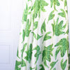 Designer Silk/Lycra Charmeuse Palm Print fabric by the yard! This fun and fashion forward deadstock fabric is perfect for creating unique and trending pieces. The green palm print set against a soft white background and the lustrous finish of this fabric will elevate any outfit.  Image of fabric drape.