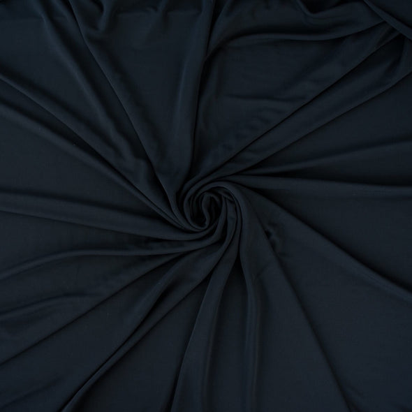 High-end Designer Black Matte jersey knit deadstock fabric by the yard, a timeless essential for every wardrobe. Achieve a designer-level look and feel, with a sophisticated black matte finish. Image of fabric body.