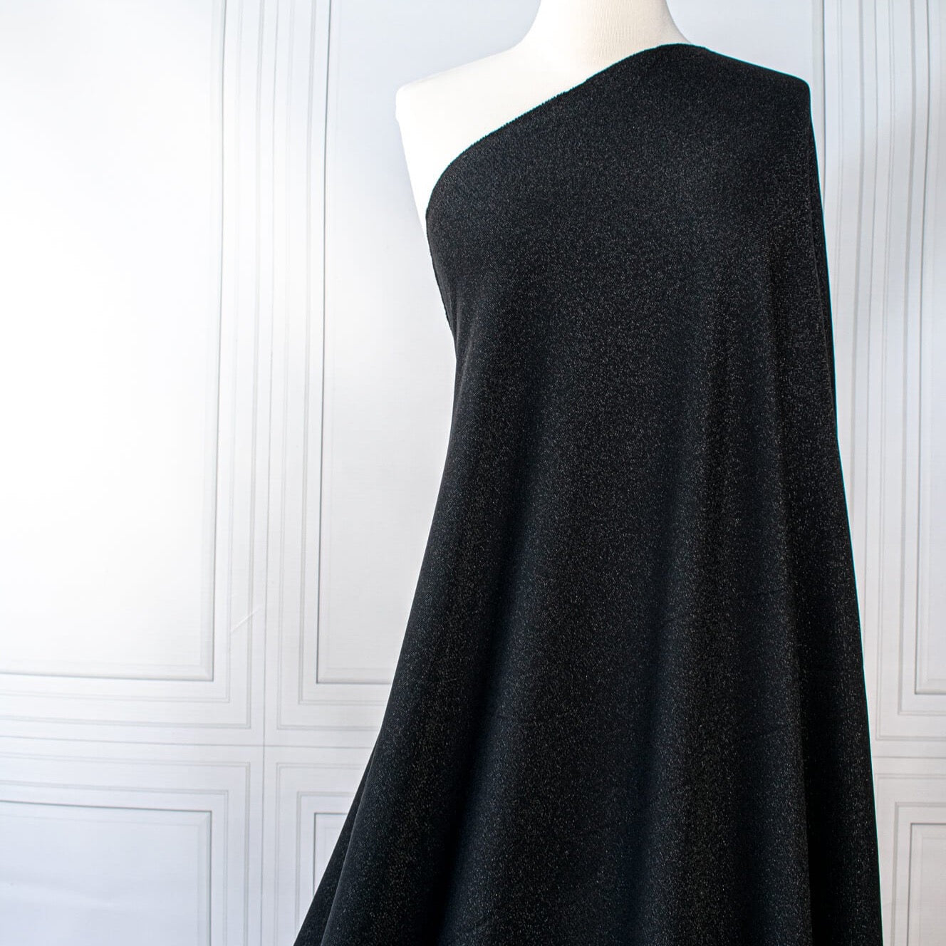 Feel glamorous with our Designer Shimmer Black Sweater Knit fabric by the yard - 'Fancy This'. This high-end designer deadstock knit in classic black with the perfect touch of sparkle. Soft and comfortable, this sweater is sure to become one of your favorite fashion staples. Image of fabric drape.