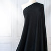 Feel glamorous with our Designer Shimmer Black Sweater Knit fabric by the yard - 'Fancy This'. This high-end designer deadstock knit in classic black with the perfect touch of sparkle. Soft and comfortable, this sweater is sure to become one of your favorite fashion staples. Image of fabric drape.