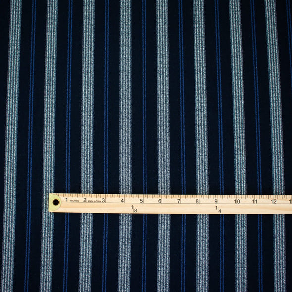 Deveaux France luxury yarn-dyed woven striped fabric featuring a crepe like texture and soft drape. Fabric with white and cobalt blue vertical stripes. Image of fabric with ruler to show pattern scale.