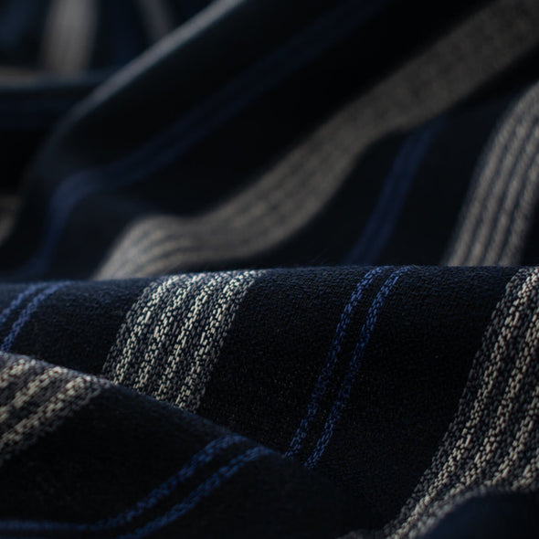 Deveaux France luxury yarn-dyed woven striped fabric featuring a crepe like texture and soft drape close up picture of fabric with white and cobalt blue vertical stripes.