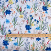 Italian crafted, soft white, viscose woven fabric by the yard. Gorgeous lilies and other florals in shades of peach, red, ivory and a vibrant blue with a fine jacquard pattern. Image of pattern scale with ruler.