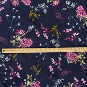 Italian Navy Floral Viscose Crepe fabric by the yard. This fabric features a beautiful design of vibrant blooms in shades of pink, and delicate sprays of flowers in soft white and ochre set against a navy background. The elegant drape and slightly textured crepe-like hand is perfect for your next high-end garment. Image of fabric design scale.