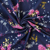 Italian Navy Floral Viscose Crepe fabric by the yard. This fabric features a beautiful design of vibrant blooms in shades of pink, and delicate sprays of flowers in soft white and ochre set against a navy background. The elegant drape and slightly textured crepe-like hand is perfect for your next high-end garment. Close up image of fabric body.