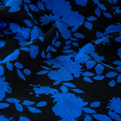 The 'Roses in Blue' Italian Jacquard fabric by the yard is just gorgeous! Luxurious and elegant, a beautiful black viscose fabric featuring a vibrant blue floral design that is sure to get you noticed.  Opaque with a nice drape and body, it is perfect for formal attire or a little something special.. Close up image.