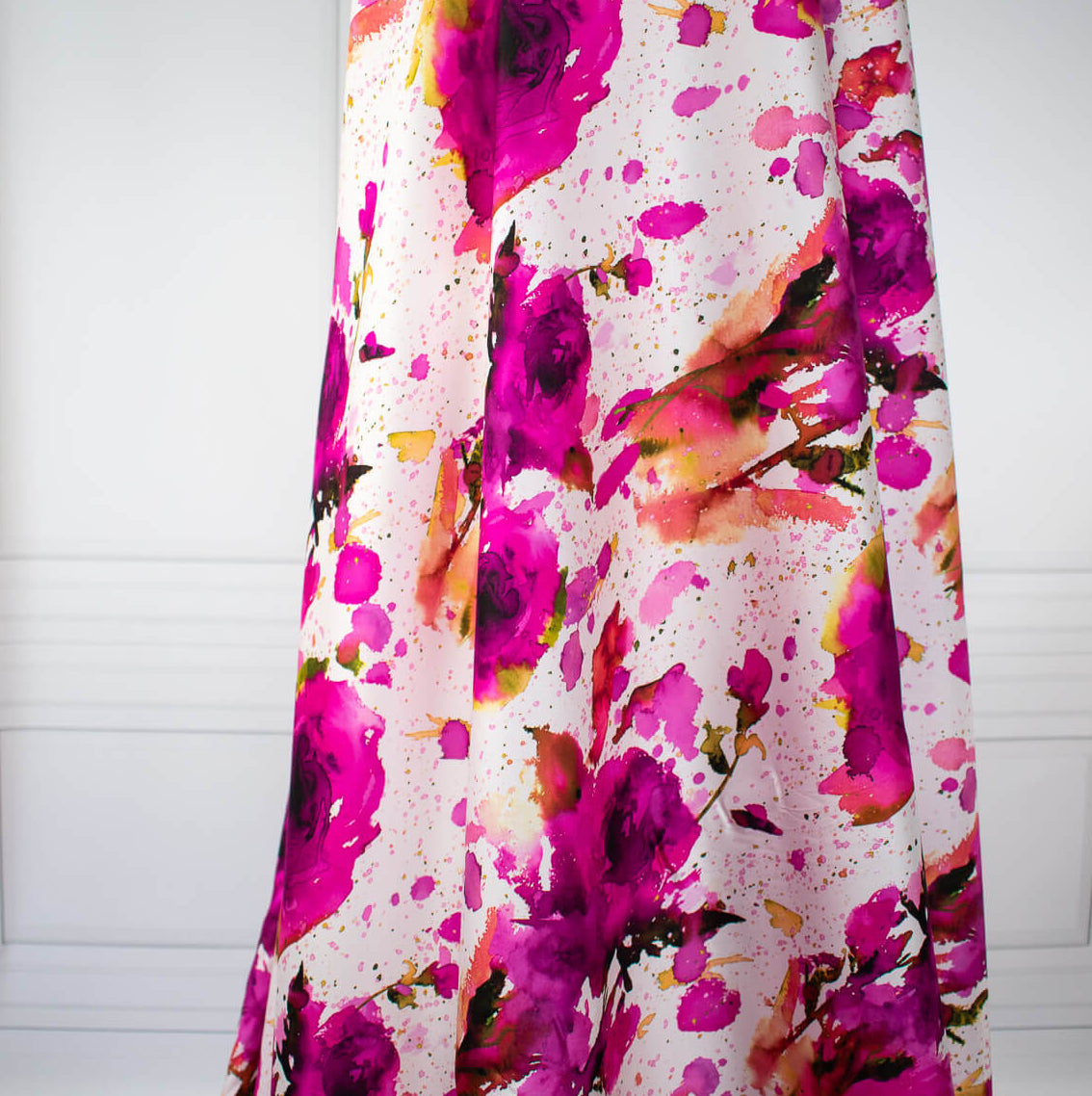 Image of designer Italian satin viscose woven fabric on dress form. Featuring an exquisite watercolor floral pattern of dark pink abstract roses against a soft white background.