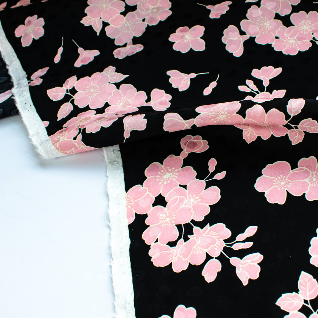 Couture Italian Viscose Floral Jacquard - 'All My Heart'! This stunning designer deadstock fabric by the yard features a gorgeous black base with delicate pink florals and ivory accents. Plus, playful and trending jacquard hearts add a touch of whimsy. 
Featuring a nice drape that falls away from the body and slightly textured hand, you'll find this fabric is perfect for formal attire or a little something special.  Image of selvedge.