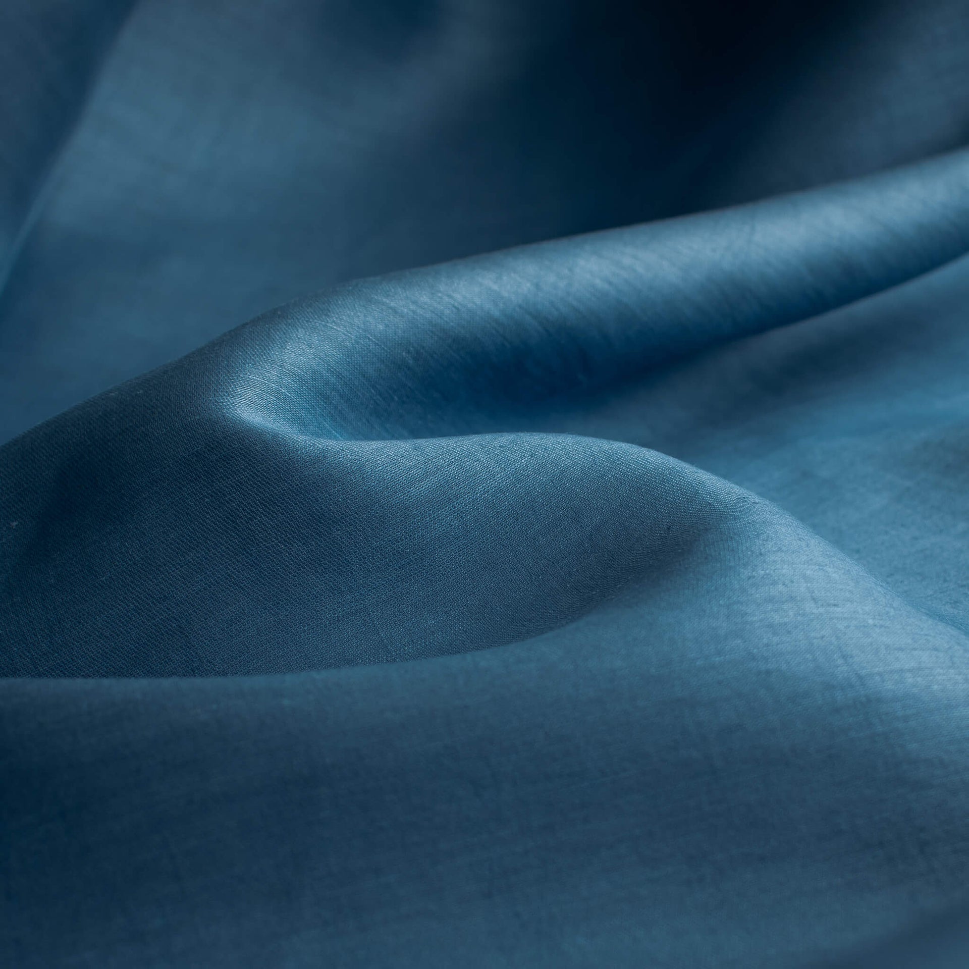 A close-up of draped Italian linen and viscose blend woven fabric by the yard in a soft Aegean blue  with soft folds and a subtle woven texture.
