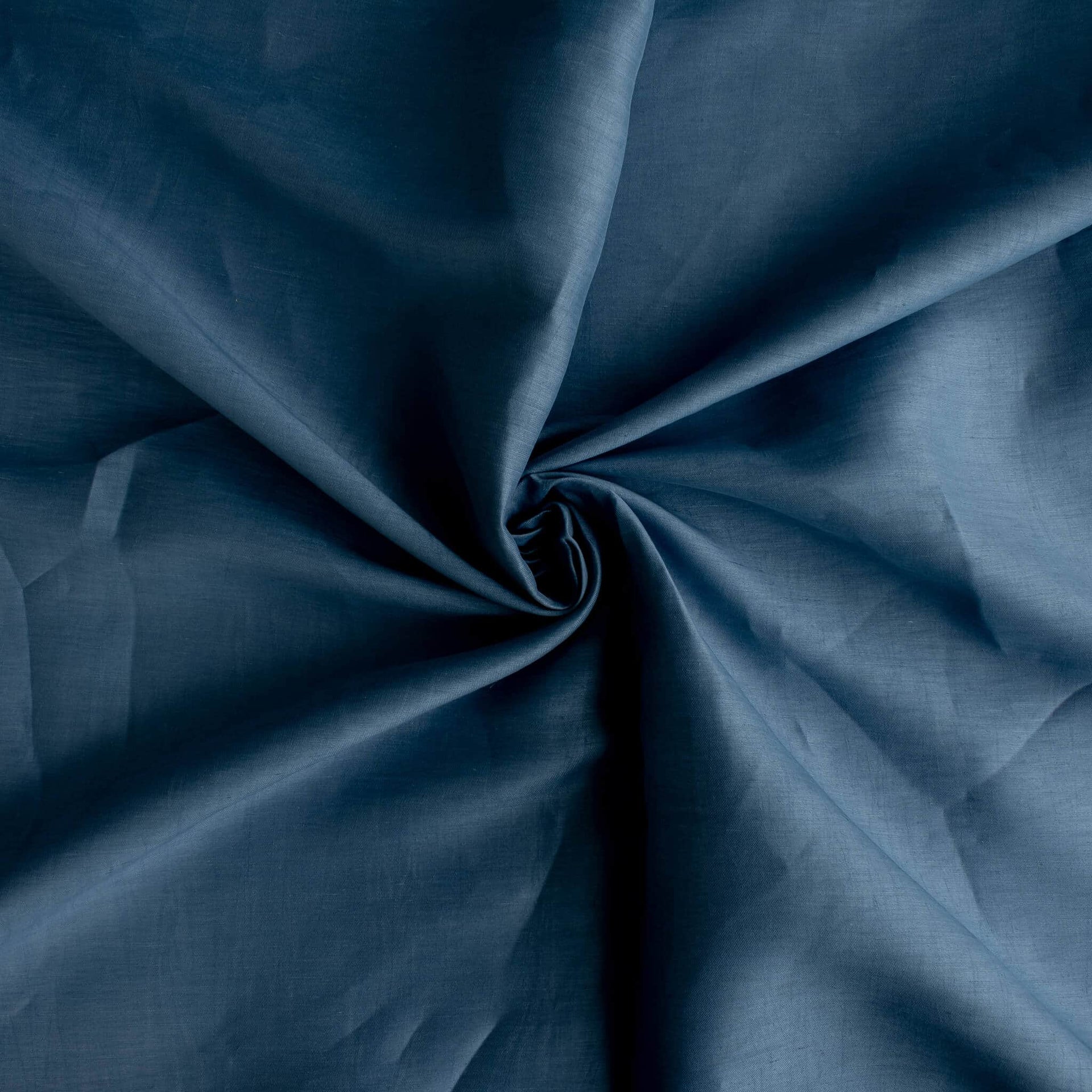A close-up of Image of Italian linen and viscose blend woven fabric by the yard in a soft Aegean blue arranged in a spiral swirl, showing its soft texture, fullness, and subtle sheen.