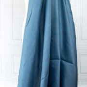 Image of Italian linen and viscose blend woven fabric by the yard in a soft Aegean blue draped on dress form against a white paneled wall background.