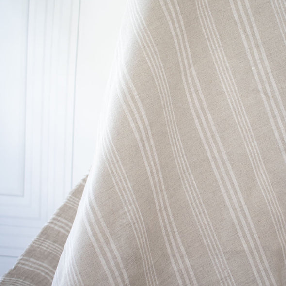 Experience the luxury of European linen fabric in a classic horizontal stripe. This medium weight linen would make a stunning jacket, skirt or pant. Featuring a wide width, textured hand, and sets of wide and narrow off white stripes. Photo of fabric drape.