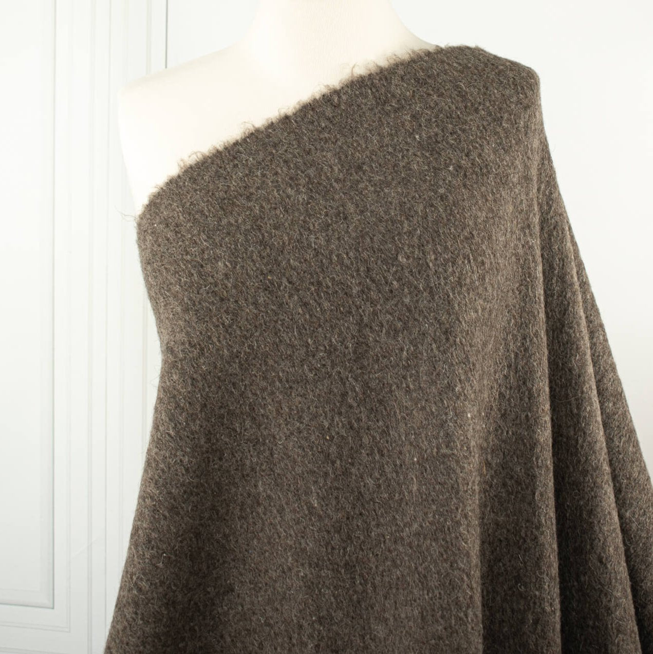 Italian Couture Wool Single Faced designer deadstock knit fabric by the yard in dark taupe and white. Perfect for chilly days this wool knit mimics a fleece with a fuzzy texture on the face and a lightly textured back. Image of fabric draped on dressform.