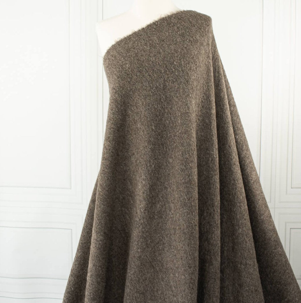 Italian Couture Wool Single Faced designer deadstock knit fabric by the yard in dark taupe and white. Perfect for chilly days this wool knit mimics a fleece with a fuzzy texture on the face and a lightly textured back. Image of fabric drape.