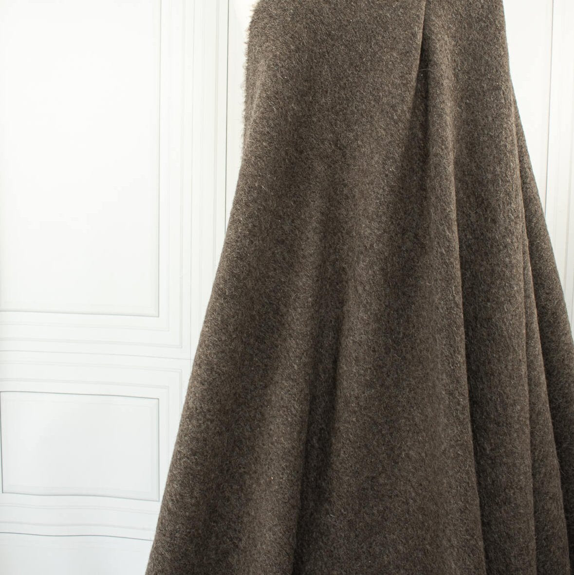 Italian Couture Wool Single Faced designer deadstock knit fabric by the yard in dark taupe and white. Perfect for chilly days this wool knit mimics a fleece with a fuzzy texture on the face and a lightly textured back. Image of fabric drape.