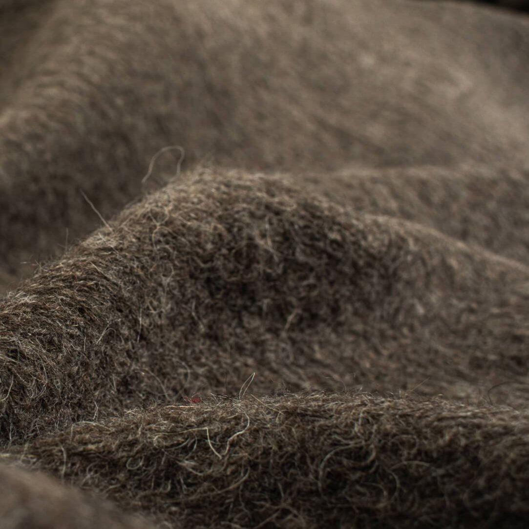 Italian Couture Wool Single Faced designer deadstock knit fabric by the yard in dark taupe and white. Perfect for chilly days this wool knit mimics a fleece with a fuzzy texture on the face and a lightly textured back. Close up image of fabric.