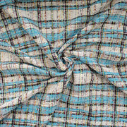 Couture Designer Italian Cotton Blend Ch@nel Boucle fabric by the yard in a gorgeous light tropical blue, black and ivory plaid accented by yellow and red fibers. This soft boucle has a textured hand and beautiful drape. Image of fabric fullness.