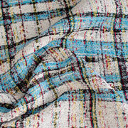 Couture Designer Italian Cotton Blend Ch@nel Boucle fabric by the yard in a gorgeous light tropical blue, black and ivory plaid accented by yellow and red fibers. This soft boucle has a textured hand and beautiful drape.  Close up image of fabric fibers.