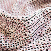 Our Couture Cotton Blend Designer Tweed fabric by the yard will have you 'Blushing' with excitement! Just in from Italy, this Ch@nel tweed is just lovely with its soft hand and elegant drape and features shades of pink, white, black, and red. Close up image of fabric texture and color.