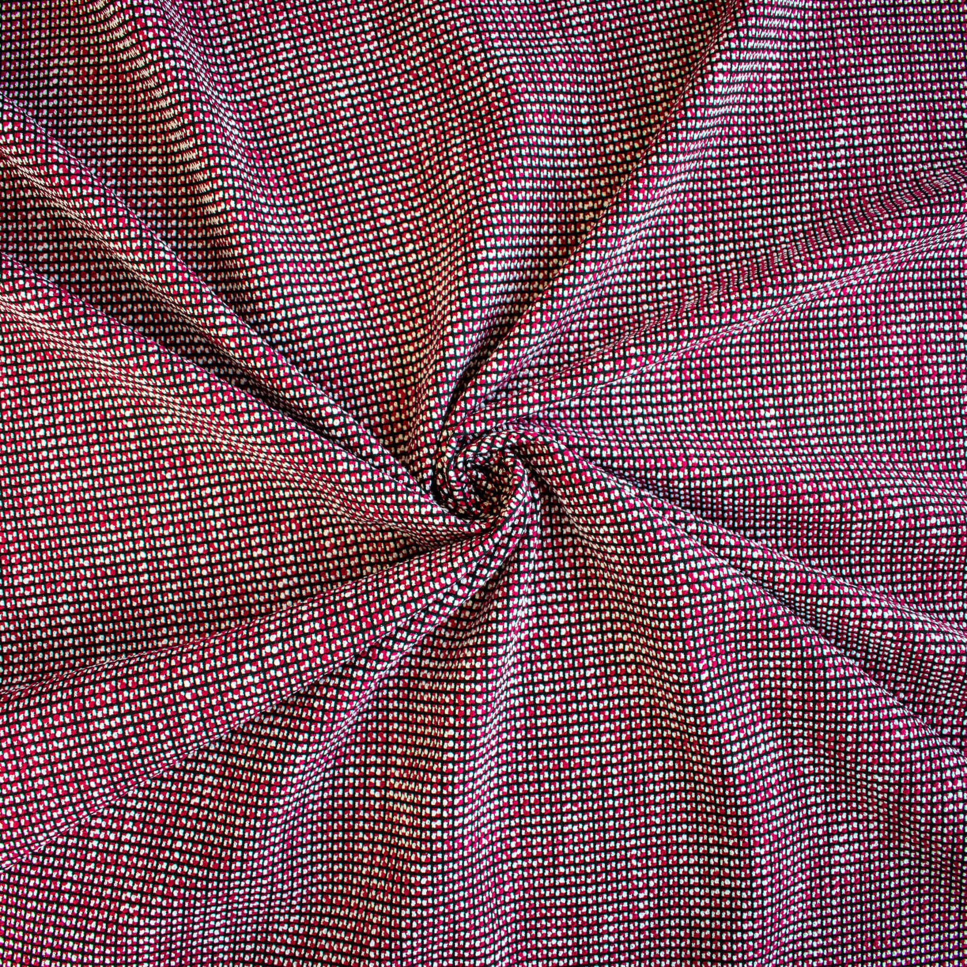 Close-up of Couture designer red, white and black textured woven fabric draped on dress form.
