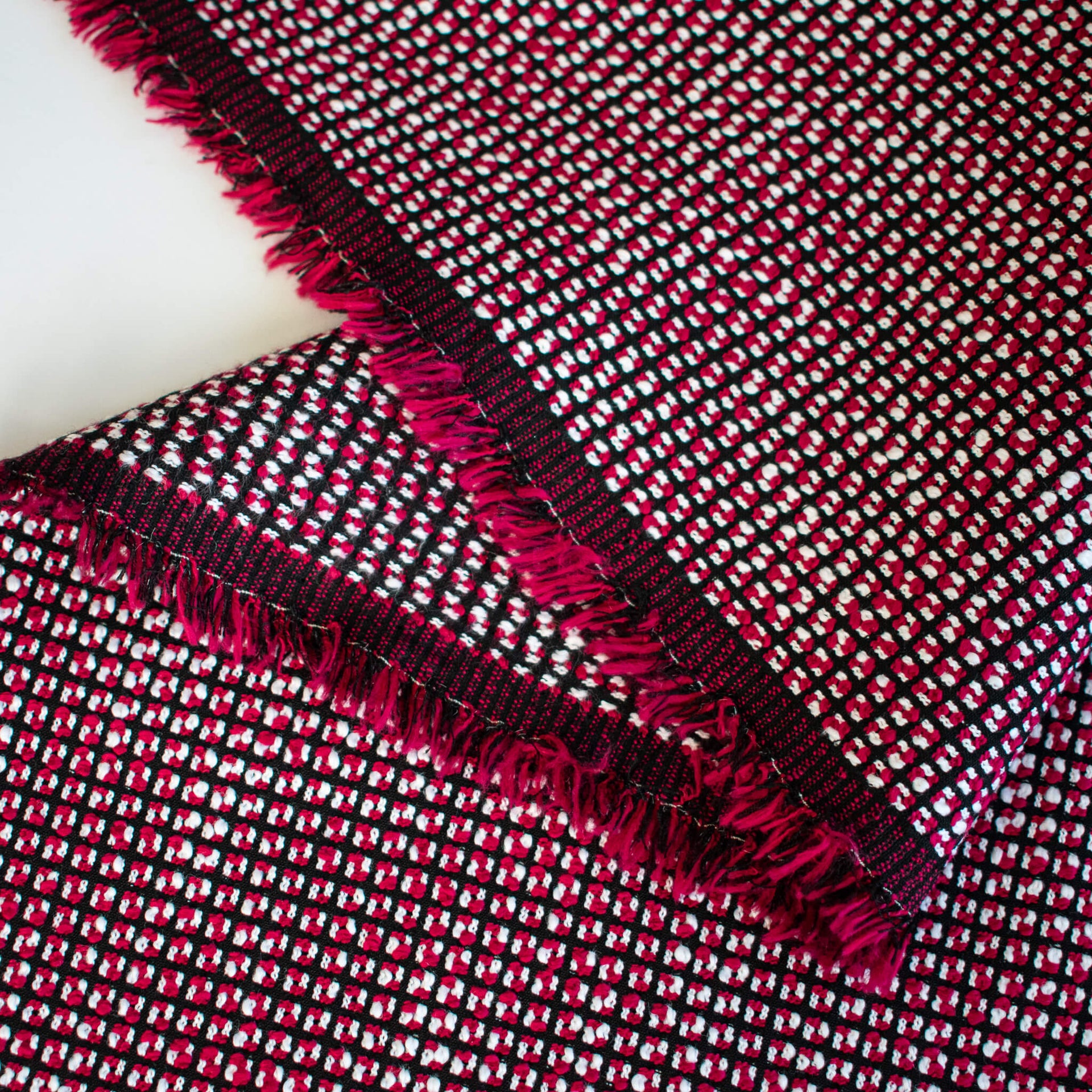 Close-up of a Couture designer woven fabric with red, black, and white pattern on a white background