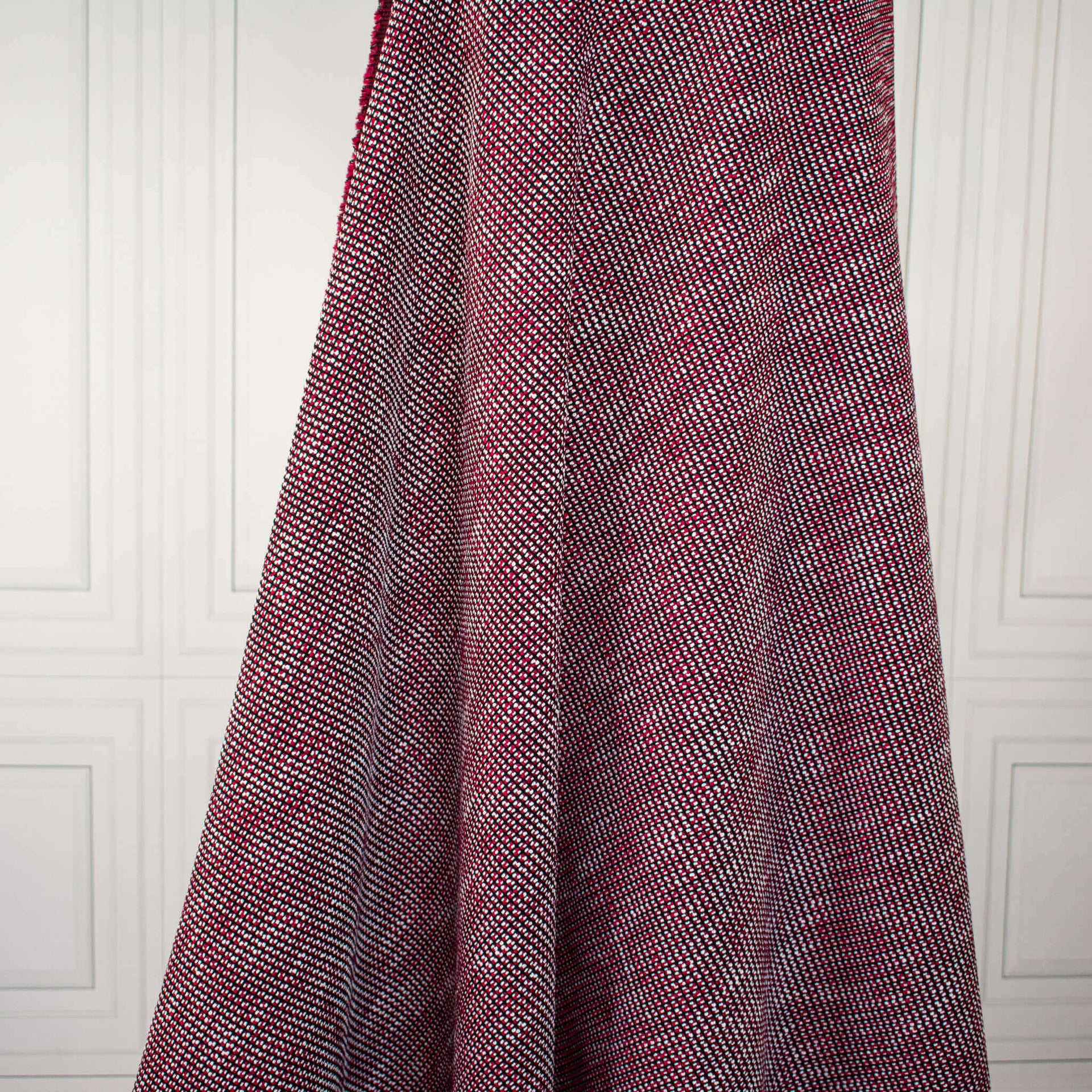 Couture red and black textured woven fabric draped on dress form.