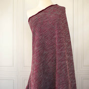 Couture textured woven fabric of red and black draped over a dressform.