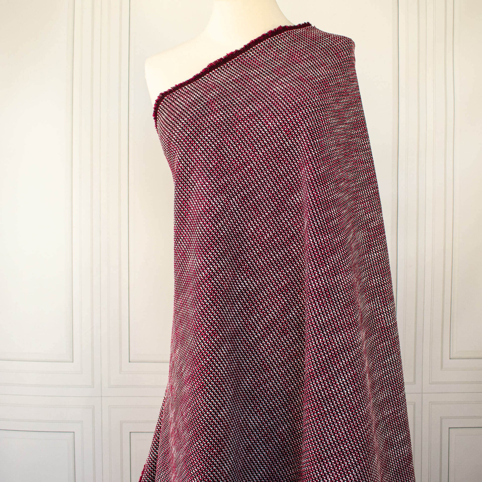 Couture textured woven fabric of red and black draped over a dressform.