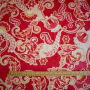 A close-up of Italian Viscose Coral Red Paisley woven fabric, with a wooden ruler at the bottom for scale.