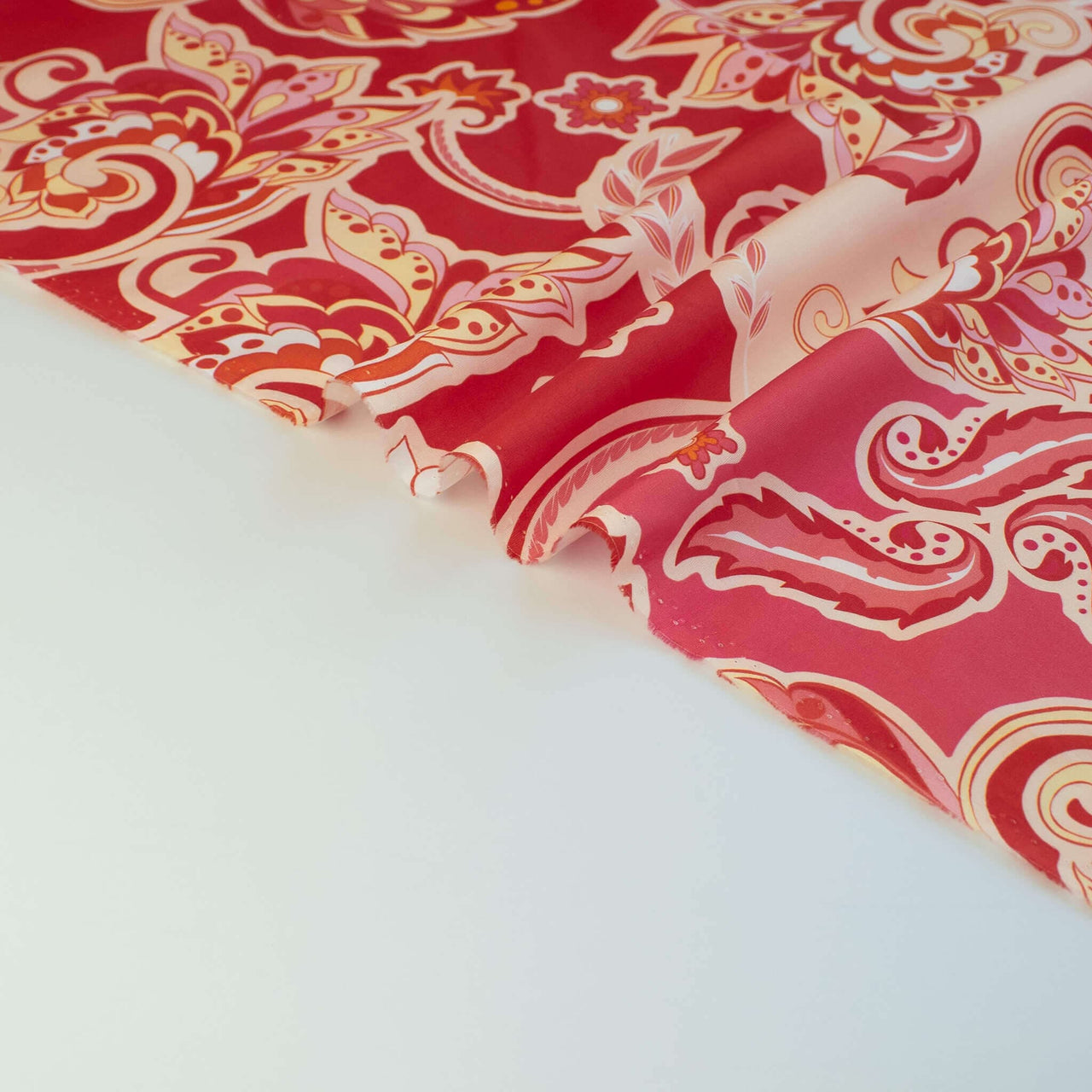 Italian Viscose Coral Red Paisley woven fabric by the yard. Image of selvedge.