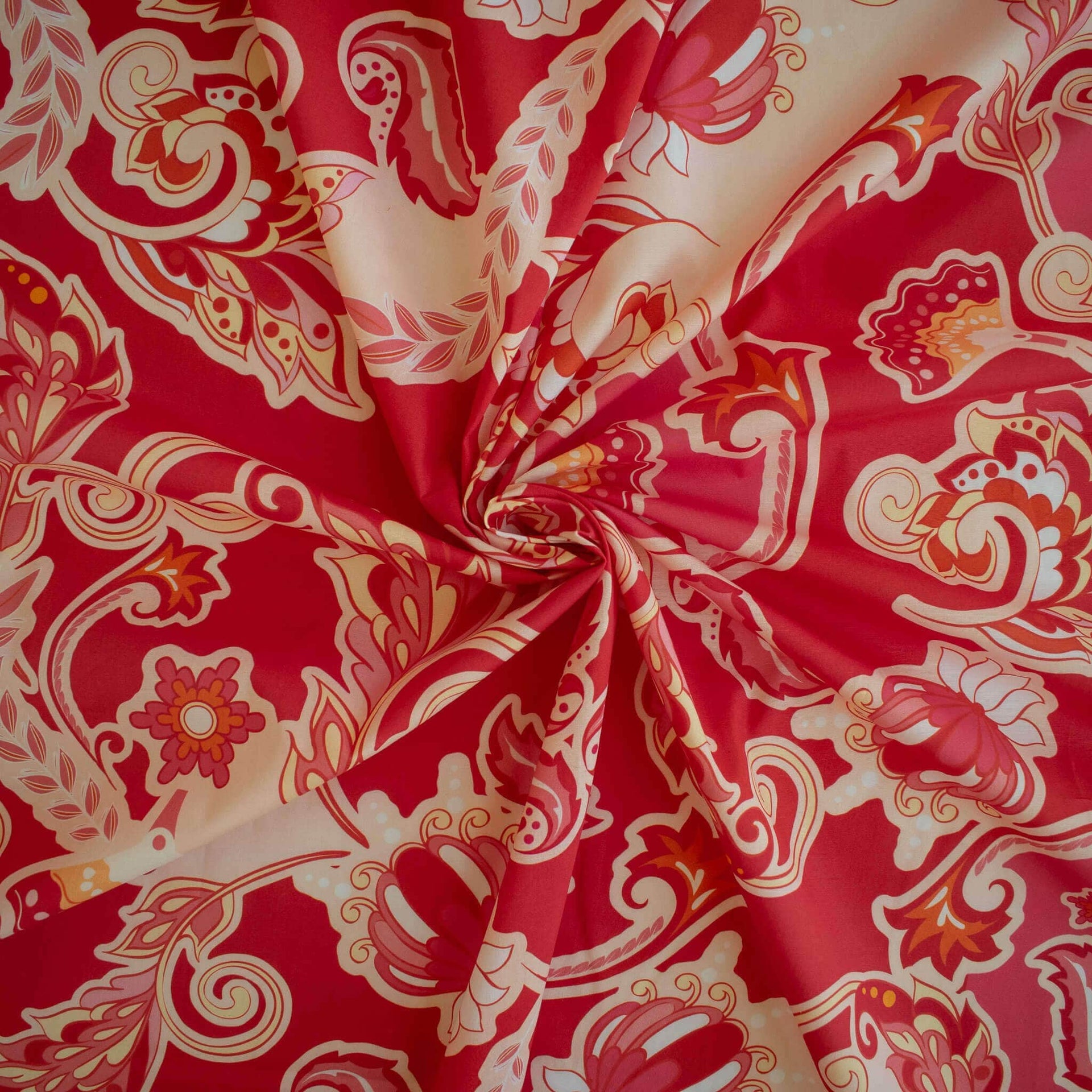 Image of Italian Viscose Coral Red Paisley woven fabric by the yard. Twirled to show fabric fullness.
